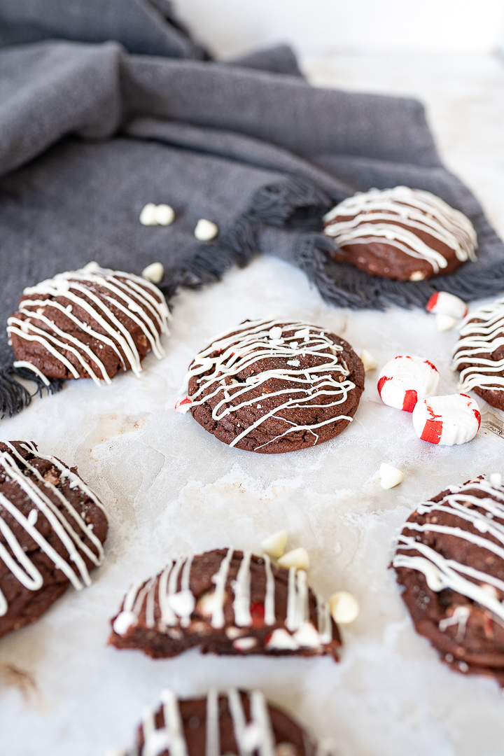chocolate peppermint cookies on the counter next to some peppermints and white chocolate chips.