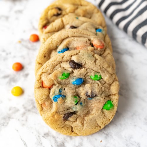 M&M cookies on the counter with m and m's sprinkled around them.