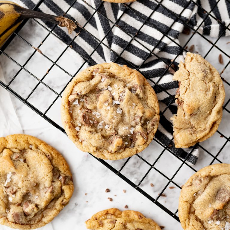Banana chocolate chip cookies on a cooling rack on the counter with a striped towel in the background.