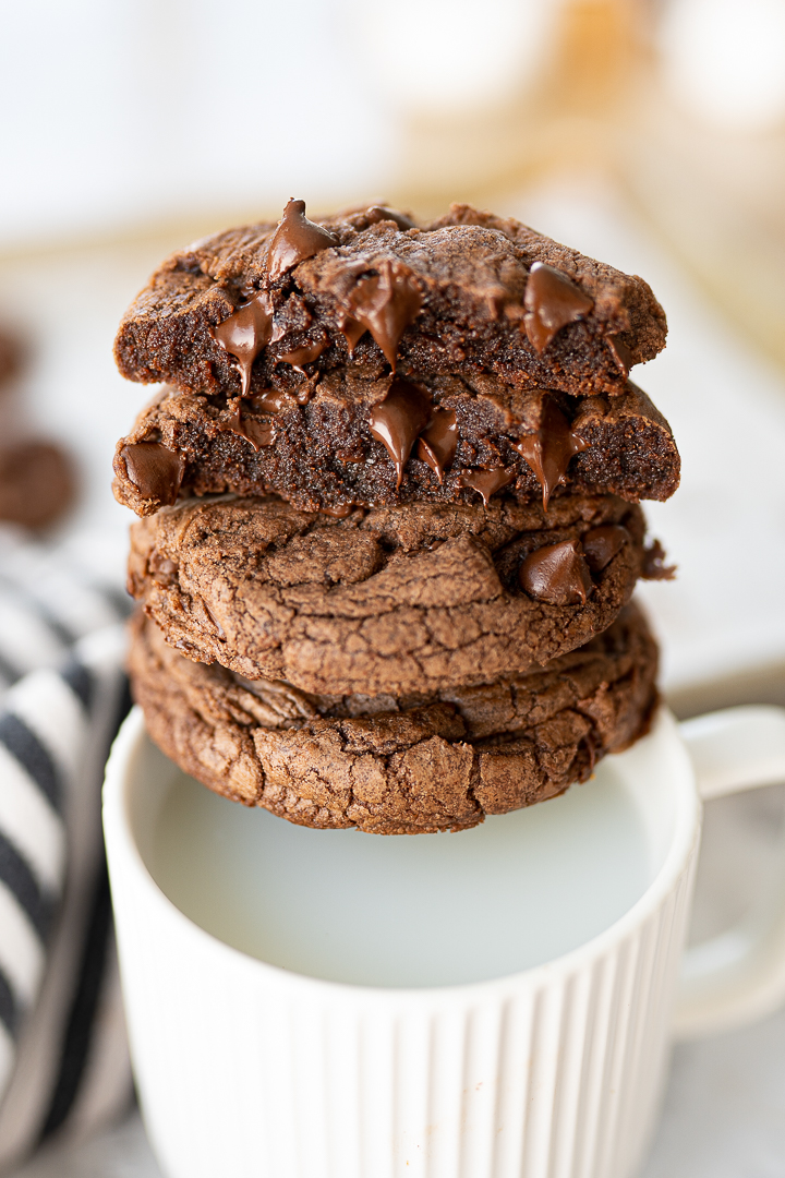 Brownie mix chocolate chip cookies stacked over a white mug of milk.