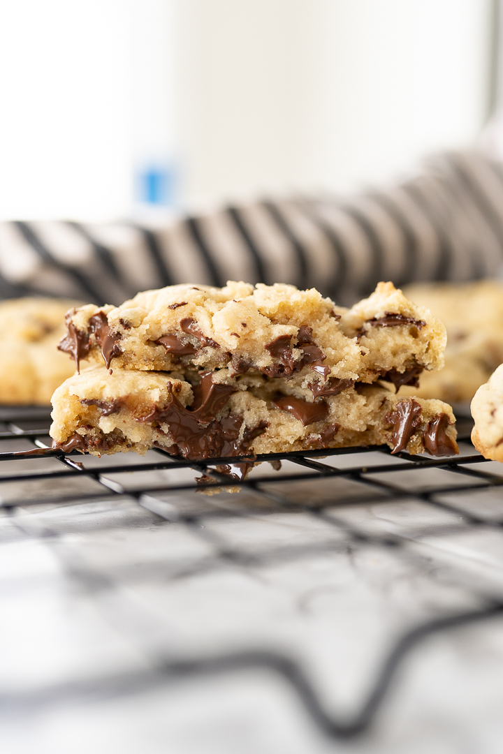 A cookie broken in half and stacked on top of each other so the gooey, chocolate chips are melting out.