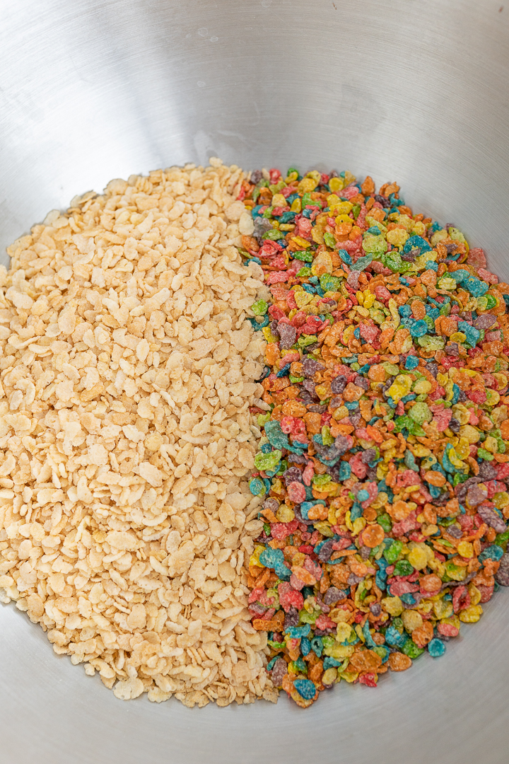 A large bowl filled with half rice krispies cereal and half fruity pebbles cereal.