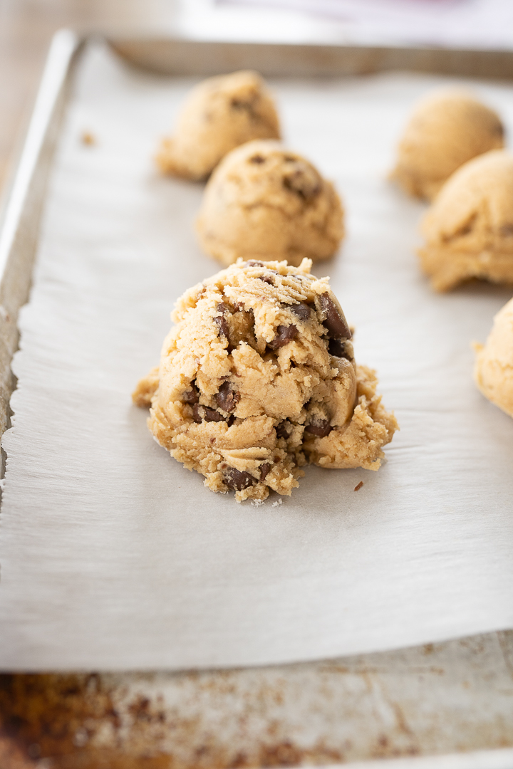 Up close photo of balls of cookie dough on parchment paper before baking.