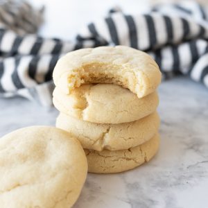 Plain sugar cookies stacked on the counter with a bite taken out of the top cookie.