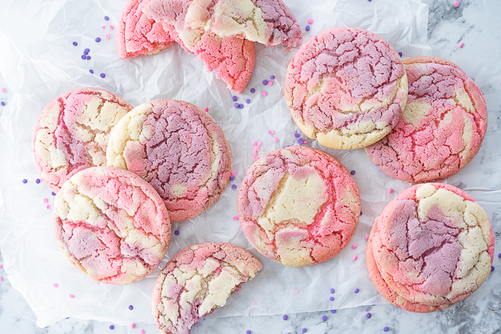 Several pink and purple Tie Dye Cookies on the counter with a few cut in half.
