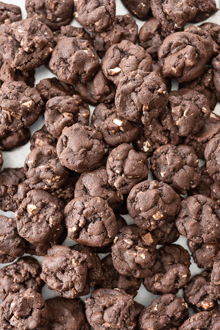 A lot of mini chocolate cookies piled on the counter.