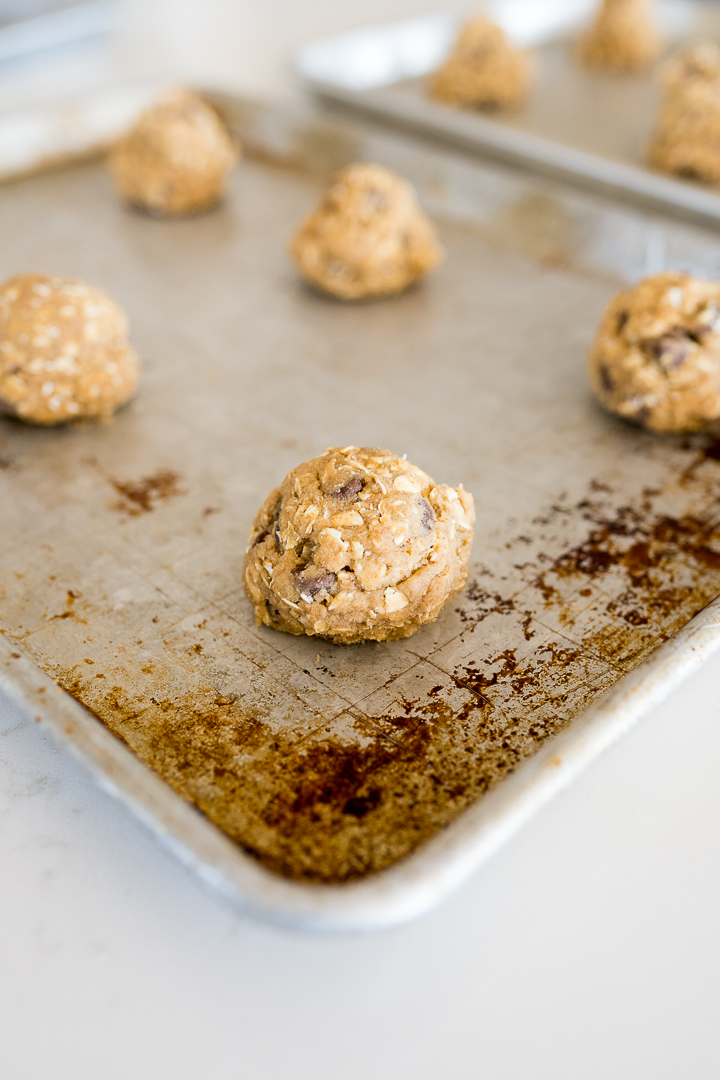 Balls of chocolate chip cookie dough on a baking sheet.