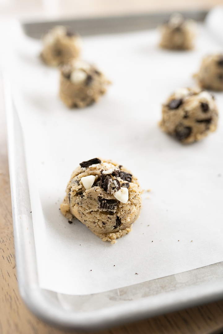 Oreo cheesecake cookie dough balls on a parchment paper lined baking sheet on the counter.