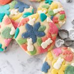 Colorful collage cookies on the counter with mini cookie cutters in the background.