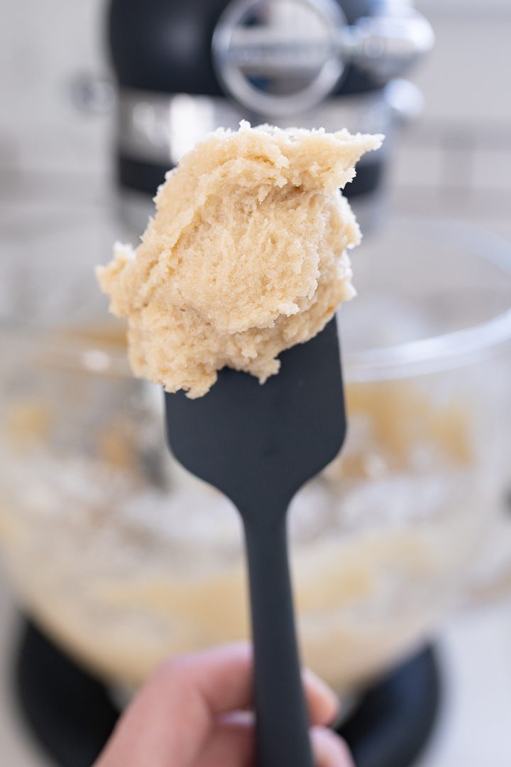 Creamed butter and sugar on a spatula. Mixer is blurred out in the background. 