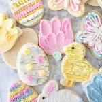 Frosted Easter sugar cookies on the counter including a chick, flower, egg, and butterfly cookie.