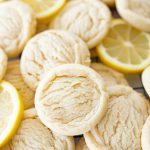 Several lemon cookies on the counter with lemon slices too.