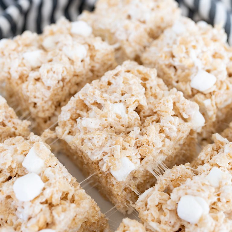 Close up image of Brown Butter Rice Krispy squares with black and white striped towel in the back.
