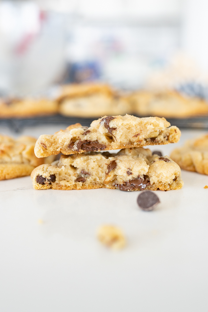 Cross section of chocolate chip walnut cookie with other cookies blurred in the background. 