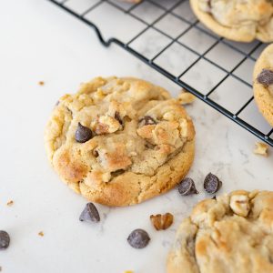 Walnut chocolate chip cookie spilling off of a wire cooling rack.