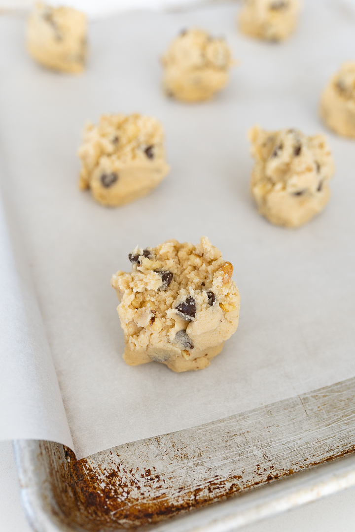 Close up of cookie dough arranged on a parchment lined cookie sheet. 