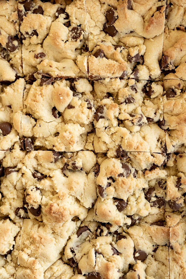 A sheet pan of baked chocolate chip cake mix bar cookies, cut into squares prior to being separated. 