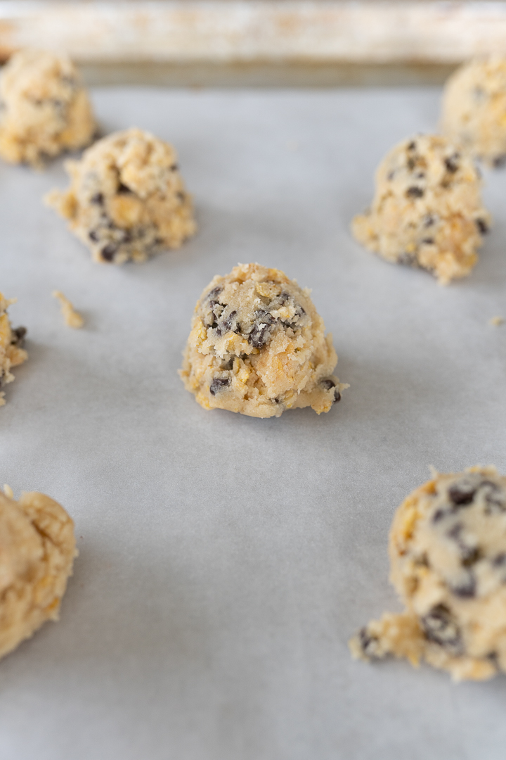 A parchment lined cookie sheet is covered with Milk Bar cookie dough balls.