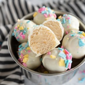 A bowl of cake balls, one is sliced in half.
