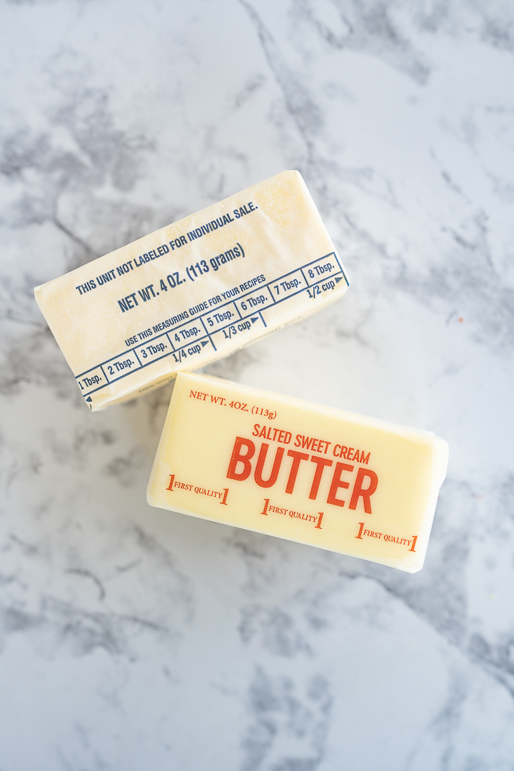 Cubes of butter and margarine lay next to each other on a counter. 