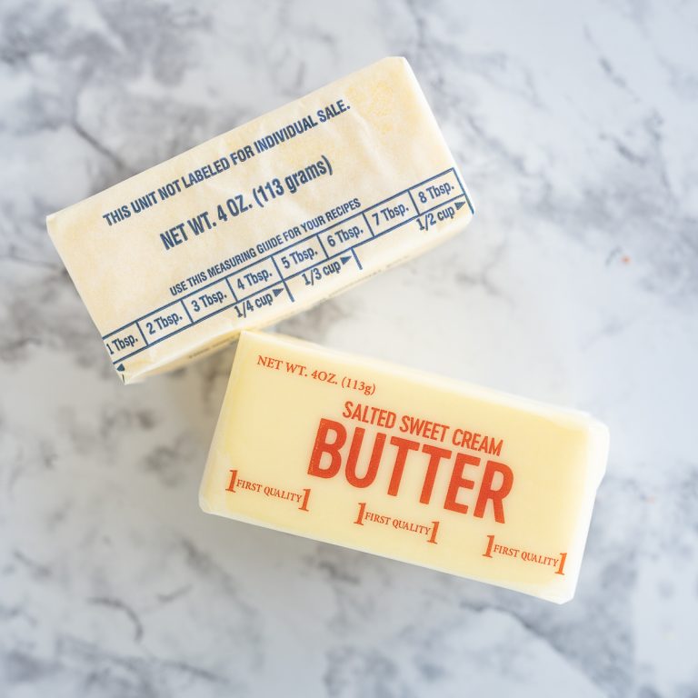 Cubes of butter and margarine lay next to each other on a counter.