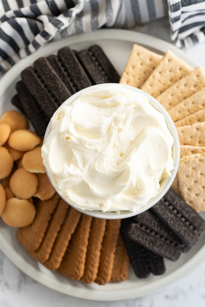 Aerial view of cheesecake dip in a bowl surrounded by cookies and crackers. 
