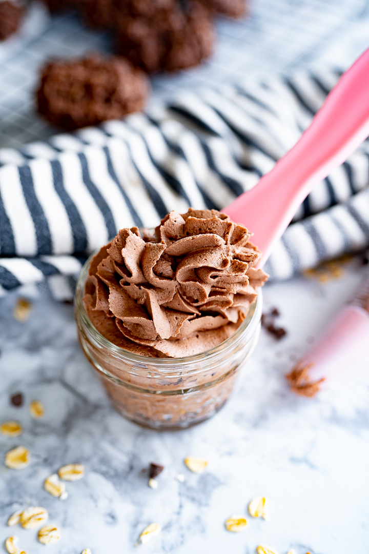 Chocolate whipped cream piped into a small mason jar with a spoon sticking out of it. 