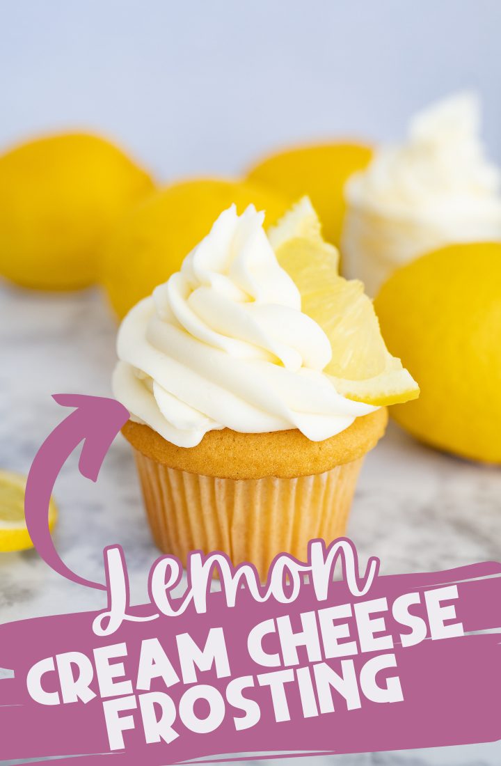 A cupcake with lemon cream cheese frosting piped on top. In the frosting is a lemon slice. In the background you can see full lemons. Across the bottom is the text, "Lemon cream cheese frosting"
