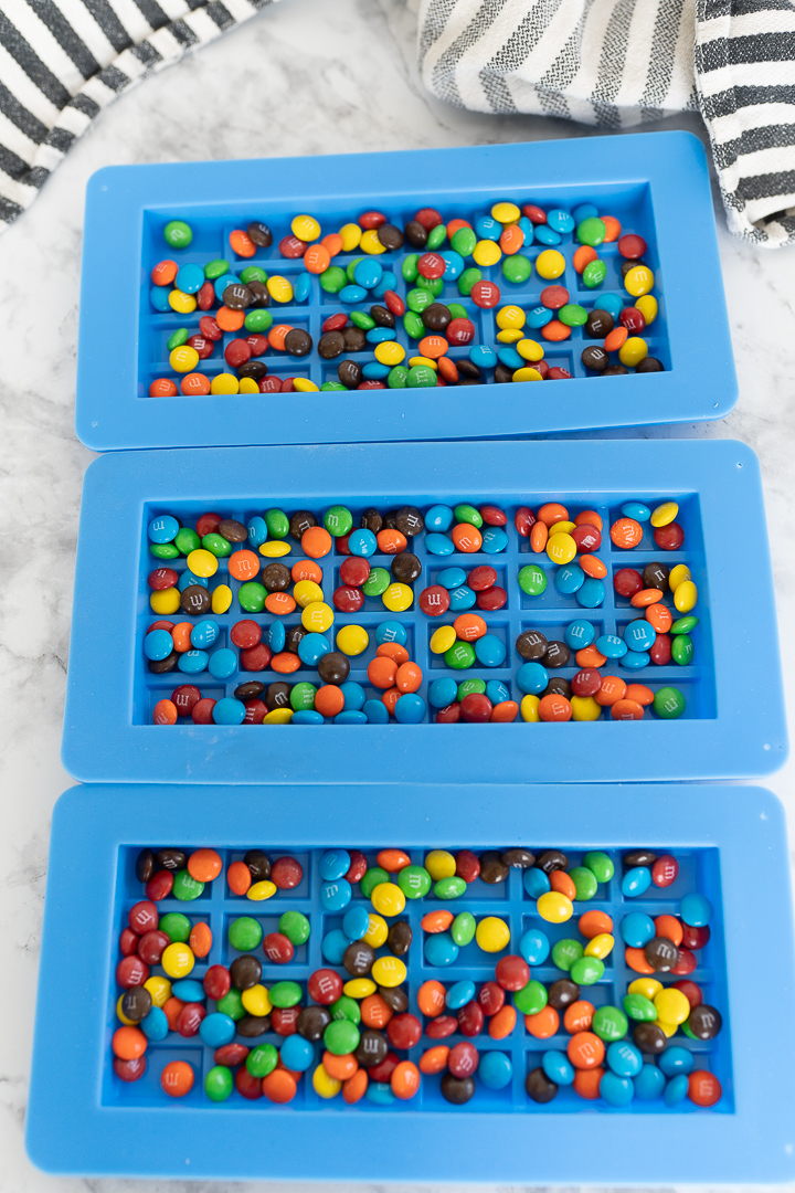 Mini M&M's spread out in chocolate bar molds.