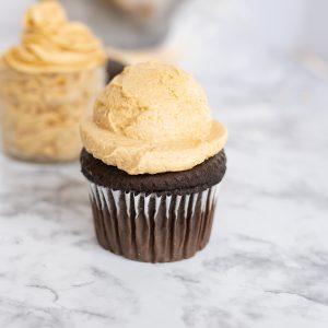 Peanut butter frosting in a heaping scoop on top of a chocolate cupcake.