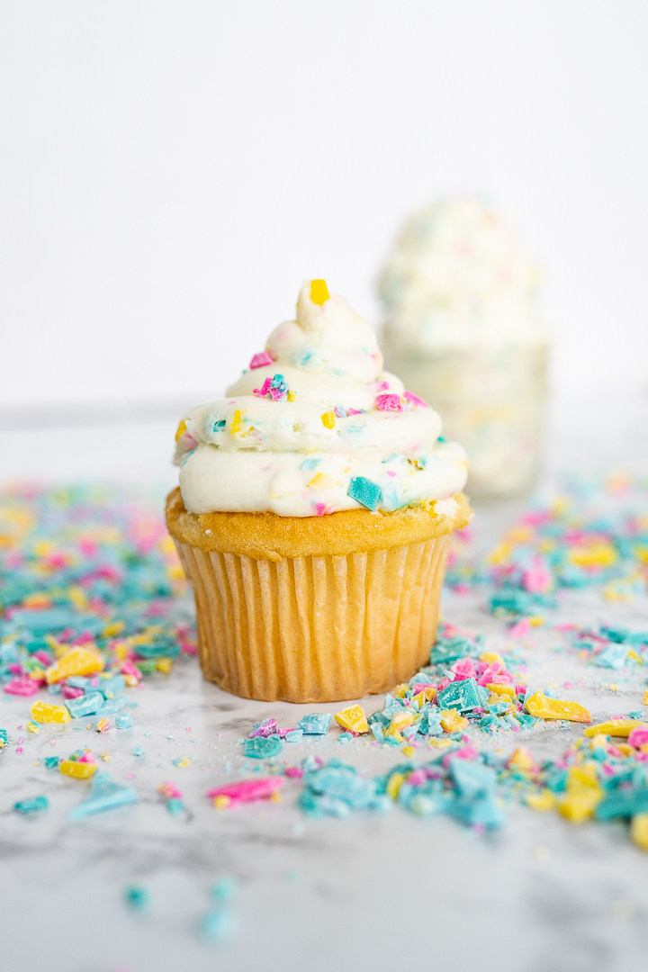 Rainbow chip frosting topping a white cupcake. 