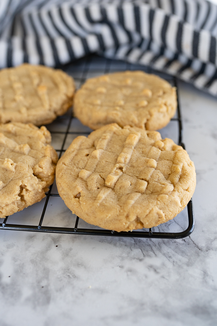 Partial image of 4 peanut butter cookies on a wire cooling rack. 