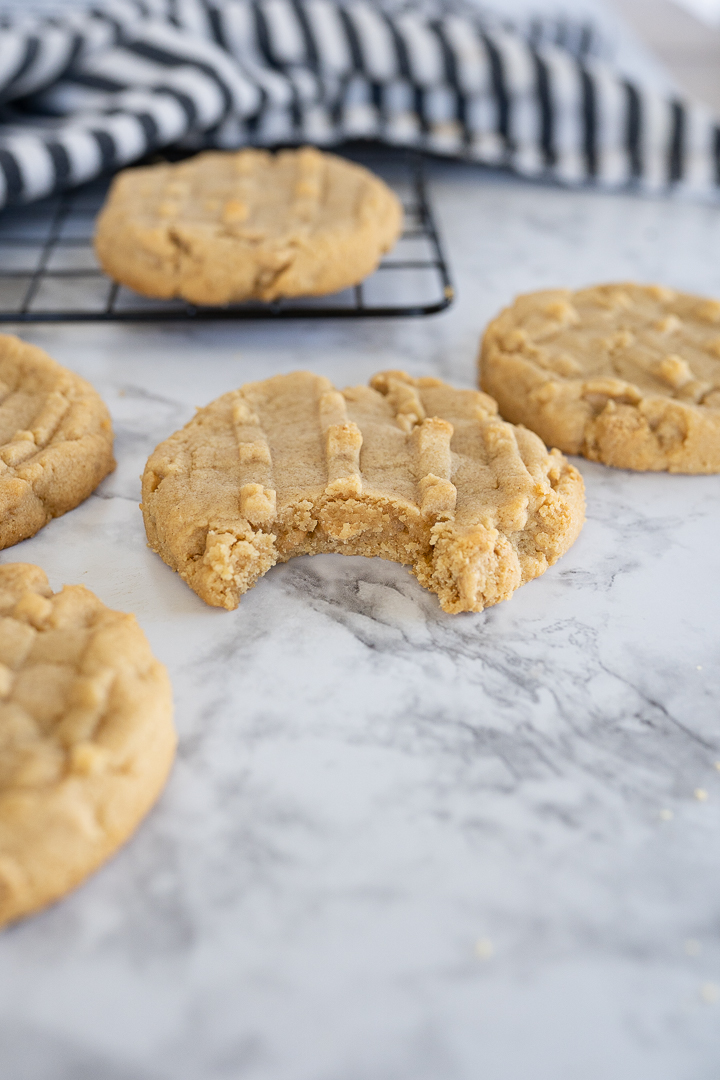Side view of peanut butter cookies sitting on a counter. One cookie with a bite taken out of it. 