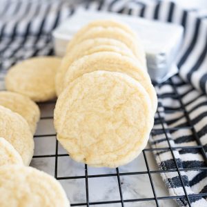 Cheesecake cookies stacked horizontally on a wire cooling rack.