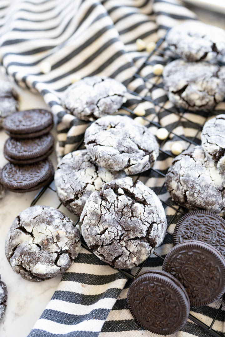 chocolate oreo crinkle cookies scattered on a striped towel with oreos. 