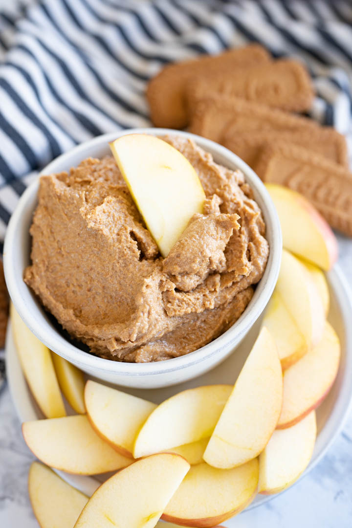 A bowl of cookie butter with an apple slice sticking out of it. 