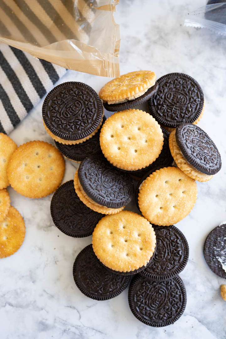 Oreo cookies and ritz crackers scattered across a counter. 