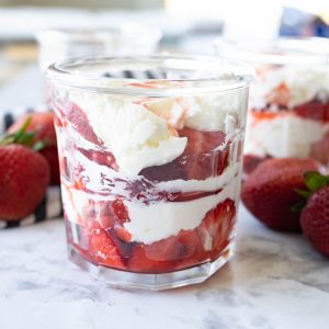 Strawberries in cream layered in a glass cup.