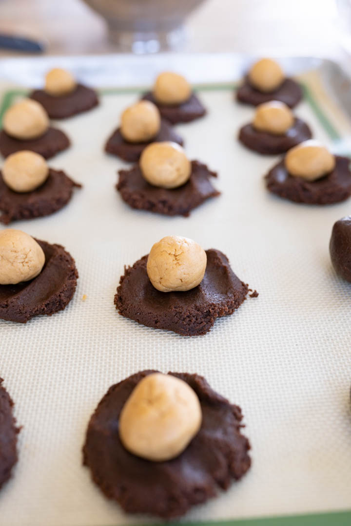 Chocolate cookie dough flattened with the peanut butter ball stacked on top prior to becoming buckeye cookie. 