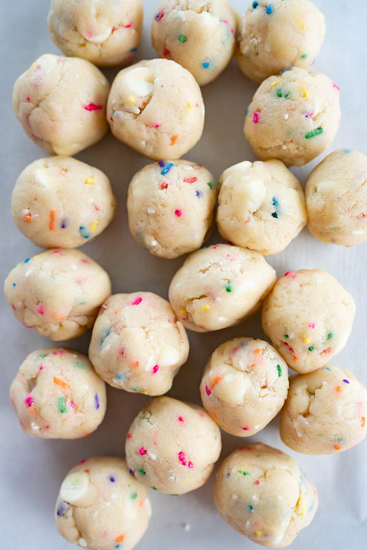 A counter filled with costco sprinkle cookie dough balls prior to being baked. 