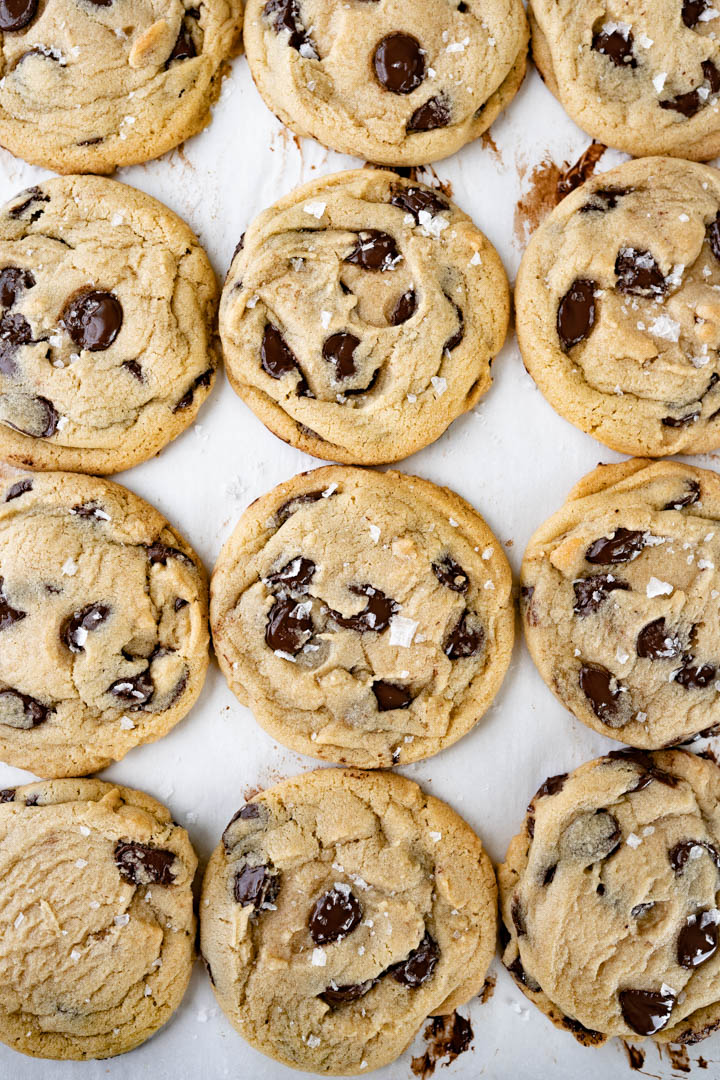 Aerial view of a tight grid of dark chocolate chip cookies. 
