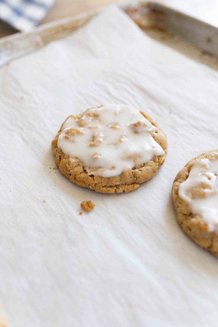Iced oatmeal cookies sitting on parchment paper. 