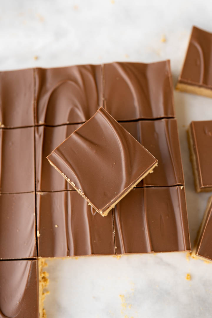 Aerial view of peanut butter bars in a sheet with one square stacked on top. 