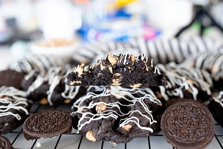 Parent trap oreo peanut butter cookies on a wire cooling rack with one cookie cut in half. 
