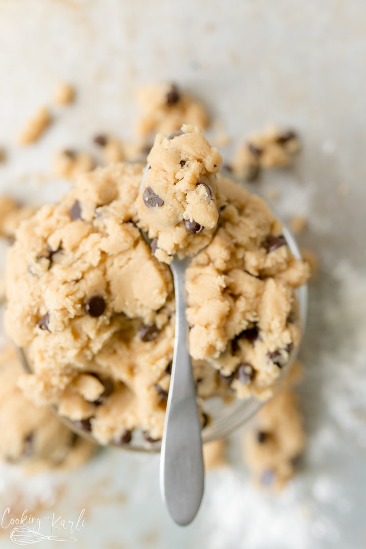 A bowl of eggless cookie dough with a spoon on top of it. 