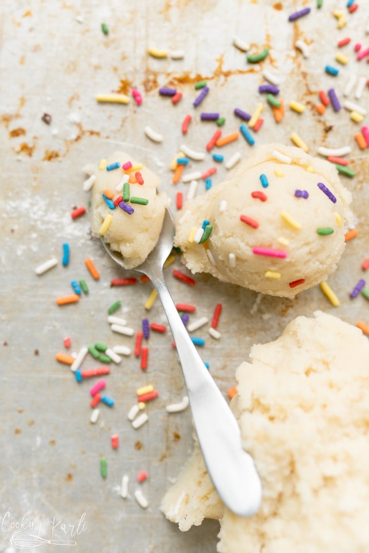 Egg free sugar cookie dough topped with sprinkles with a spoon next to it. 