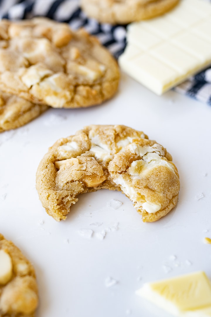 White macademia nut cookie with a bite out of it. 