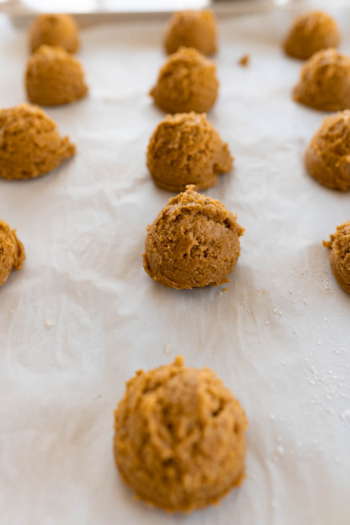 Pumpkin crinkle cookie dough balls on a cookie sheet prior to being baked. 