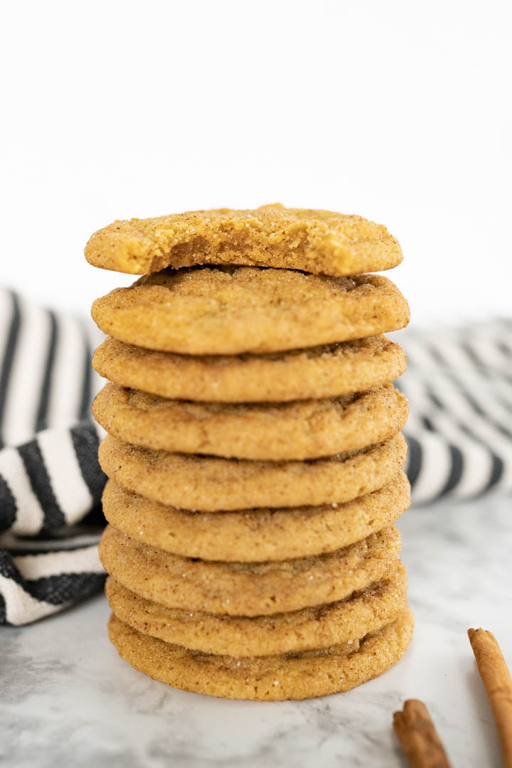 Side view of chewy pumpkin cookies stacked tall. The top cookie has a bite out of it. 