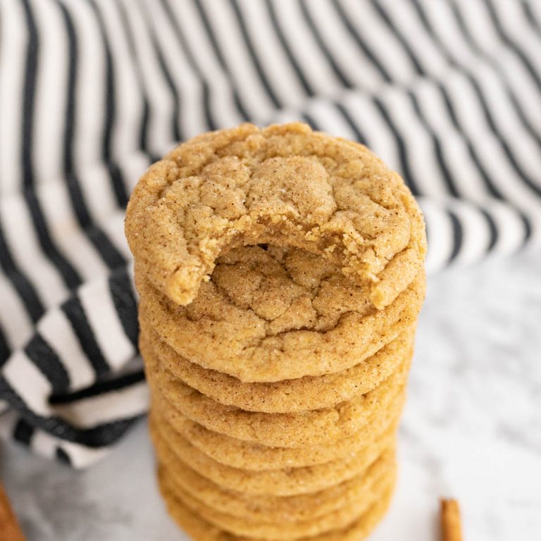 A tall stack of chewy pumpkin cookies. The top cookie has one bite out of it.